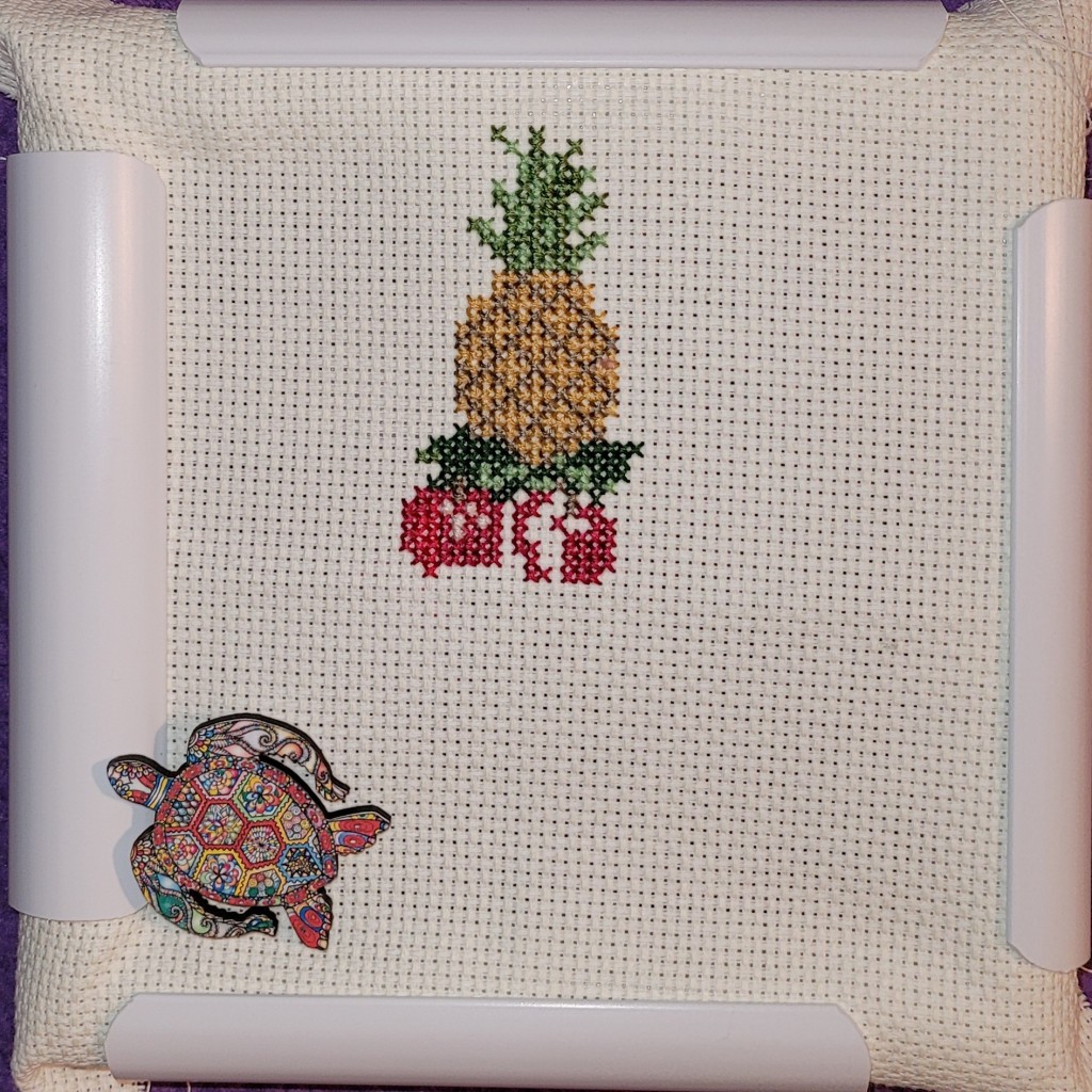 Work In Progress - Christmas tree cross stitch - pineapple on top with two partial apples below, rest of tree to come
